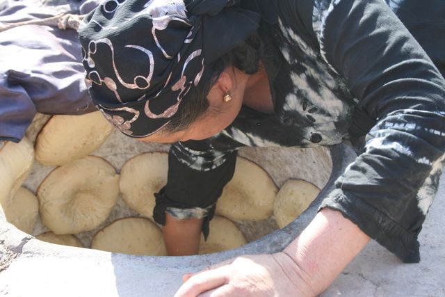 donna uigura a Kashgar nello Xinjiang cinese cuoce il pane in forno di terracotta