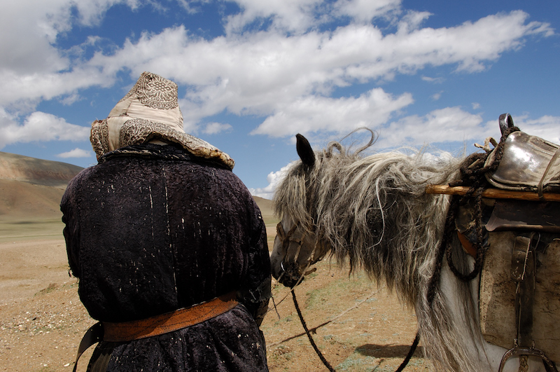 Un nomade di etnia kazaka con il suo cavallo nelle steppe aride degli Altai in Mongolia